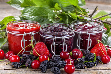 strawberry, cherry and mulberry jam on a rustic table