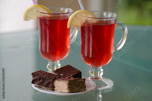 Red drink in glass with cake