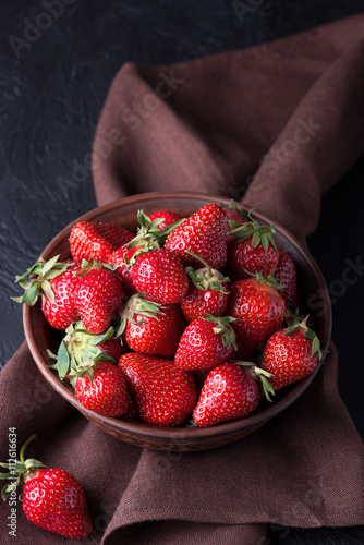 Fresh strawberry in the brown bowl on dark table