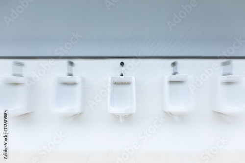 Line of white urinals in public bathroom with zoom blured