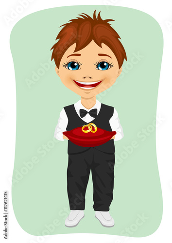 Little boy holding wedding rings on cushion. Ring bearer