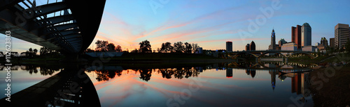 Panoramic from under the Main Street bridge at dusk with vibrant sky and smooth reflection in the river.