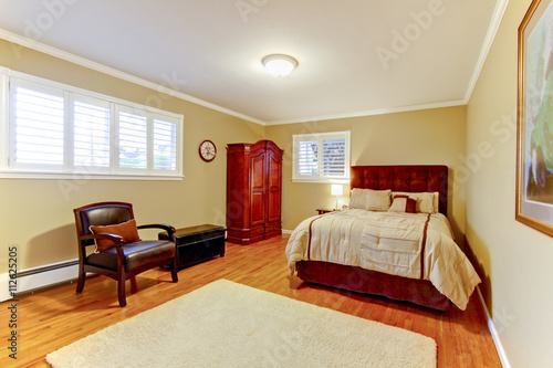 Guest bedroom with suede bed frame and hardwood floor. 