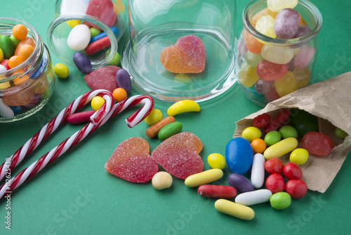 Mixed colorful fruit candies and jellies on green background