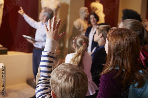 Pupils And Teacher On School Field Trip To Museum With Guide