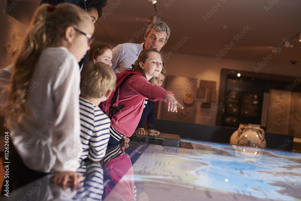 Pupils On School Field Trip To Museum Looking At Map - obrazy, fototapety, plakaty 