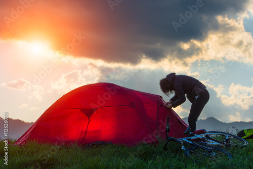 Travelling by bike alone. Young tourist sporty woman with tent a