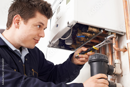 Male Plumber Working On Central Heating Boiler photo