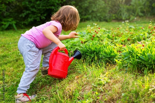 Cute little girl in the garden,watering plants.