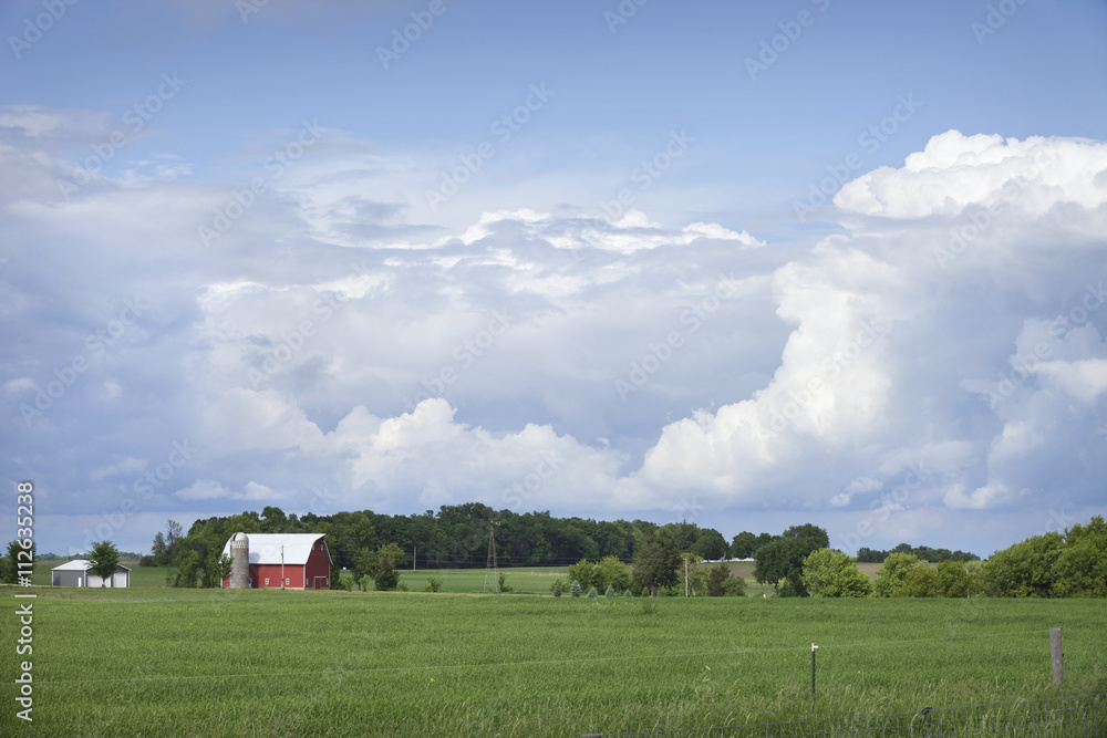 Obraz premium Red barn and field below dramatic cloudscape