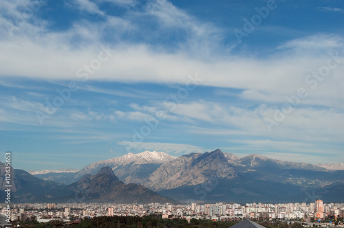 City and mountains background. Sunny landscape with blue sky