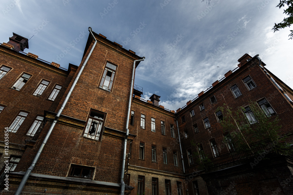 The gloomy and deserted hospital or a house with broken windows and contrastingÂ sky.