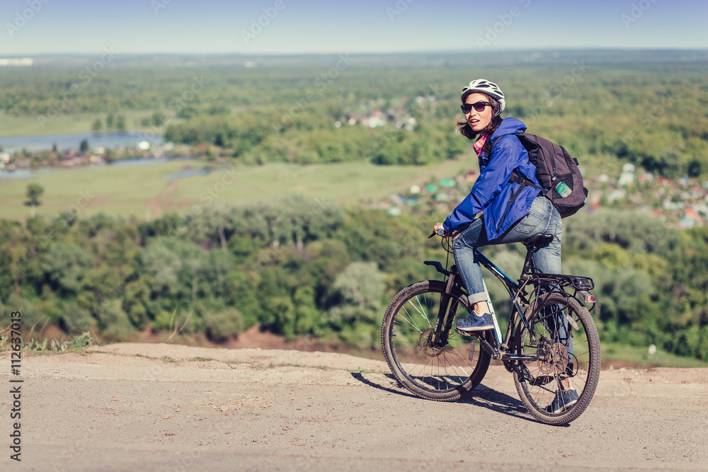 Fototapeta premium Thoughtful young woman with helmet riding bike in forest