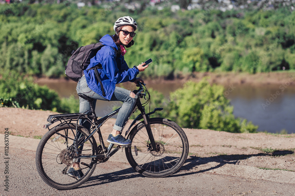 Young woman use of the cellphone at countryside while cycling