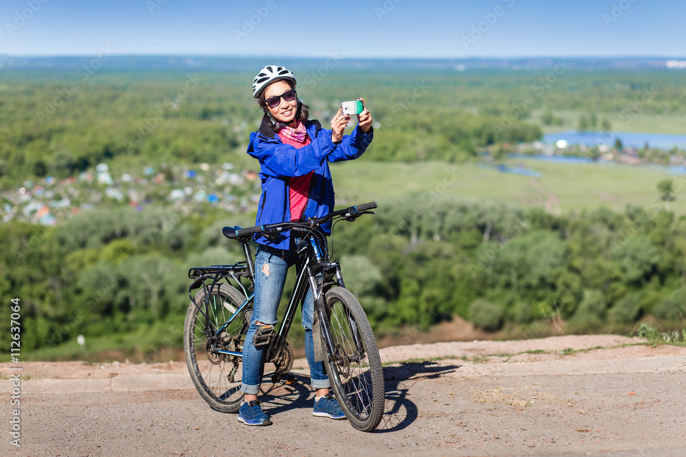 Fototapeta premium Beautiful woman cyclist take a self portrait with smart phone