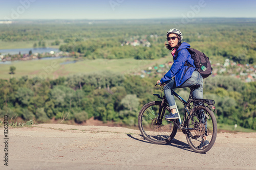 Thoughtful young woman with helmet riding bike in forest