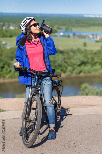 Sport young woman drinking water after doing some bicycle exerci photo