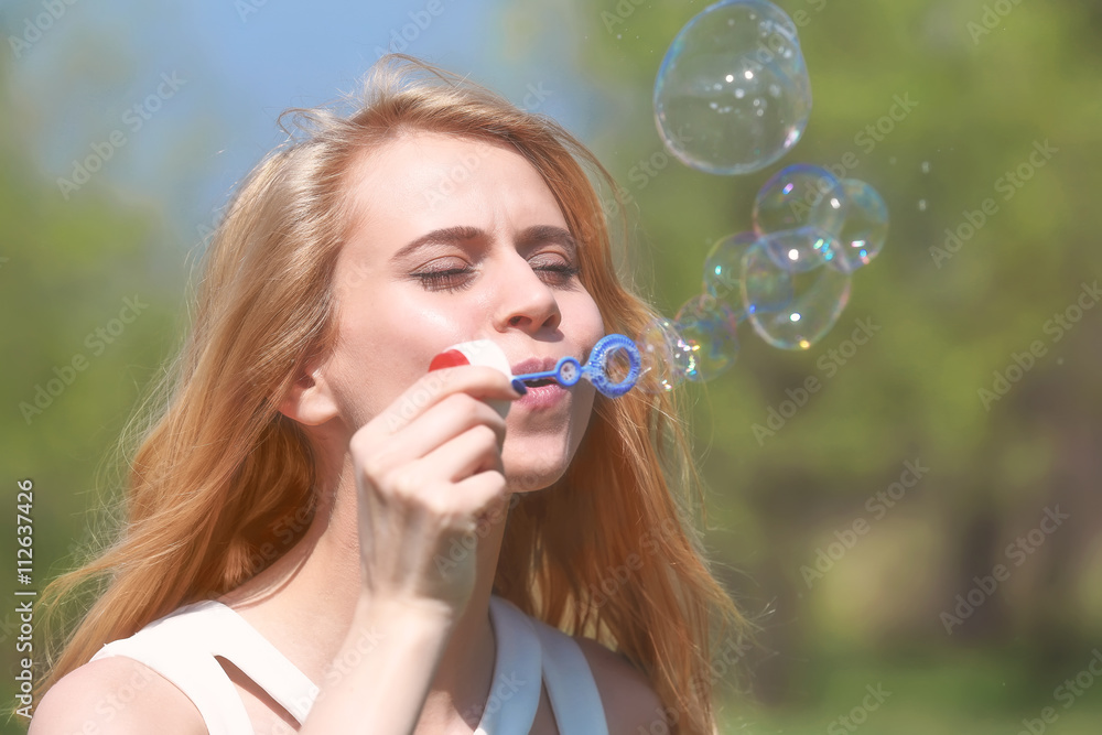 Young beautiful woman with bubbles on meadow