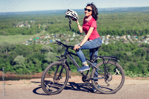 Fototapeta Naklejka Na Ścianę i Meble -  Bike helmet - woman putting biking helmet on during bicycle ride.