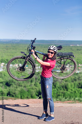 Young woman biker hold her bike up happy smiling outdoor. Cross country female biker relaxing after riding a bicycle race