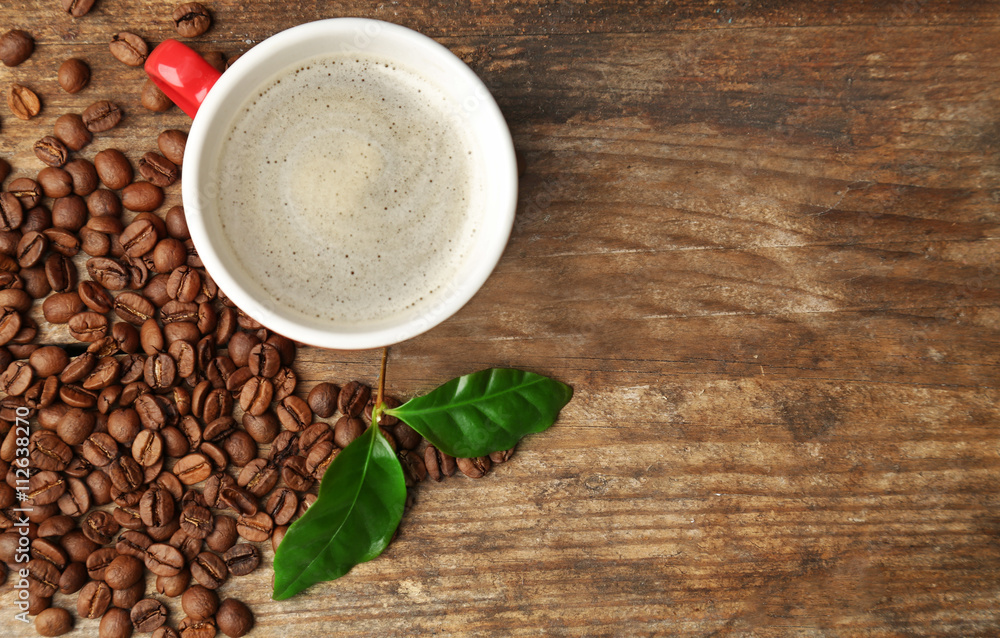 Cup of coffee with beans and leaves on wooden background Cup of coffee with beans and leaves on wooden background