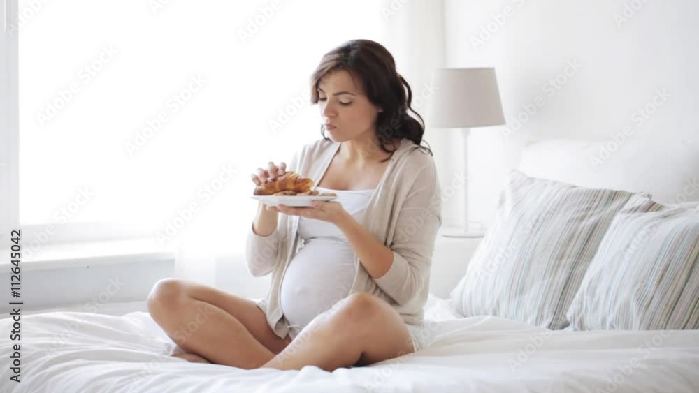 pregnant woman eating croissant in bed at home 4