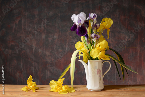 Fototapeta Naklejka Na Ścianę i Meble -  Yellow iris in a ceramic vase on a wooden table