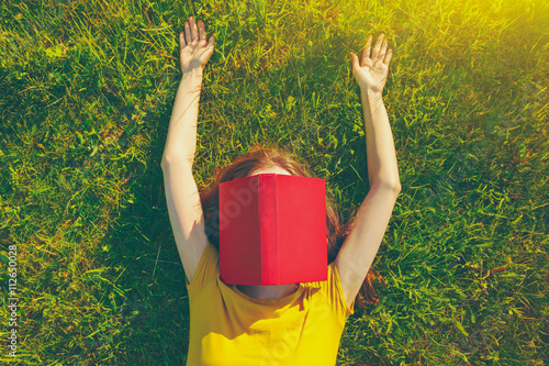 Obraz na plátne girl reading book lying in warm summer grass. view from above