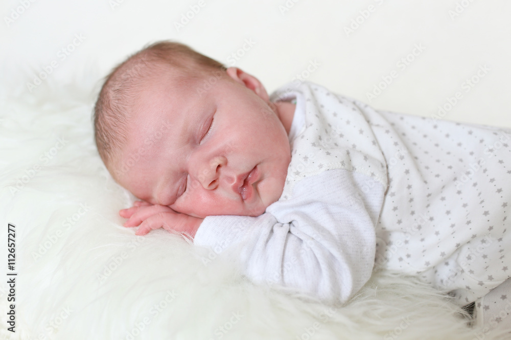 3-weeks newborn girl sleeps on fur white plaid 3-weeks newborn girl sleeps on fur white plaid