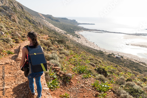 a girl walking with a solar-cell panel on the backpack