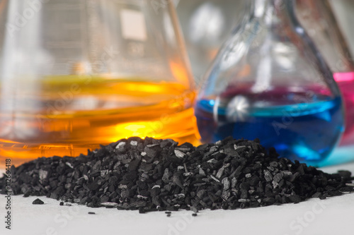 Bild auf Leinwand Charcoal fines against background of flasks with colored liquids