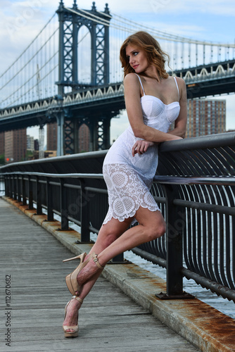 Young fashionable woman wearing sexy lace dress posing on the pier with Manhattan Bridge on the background.