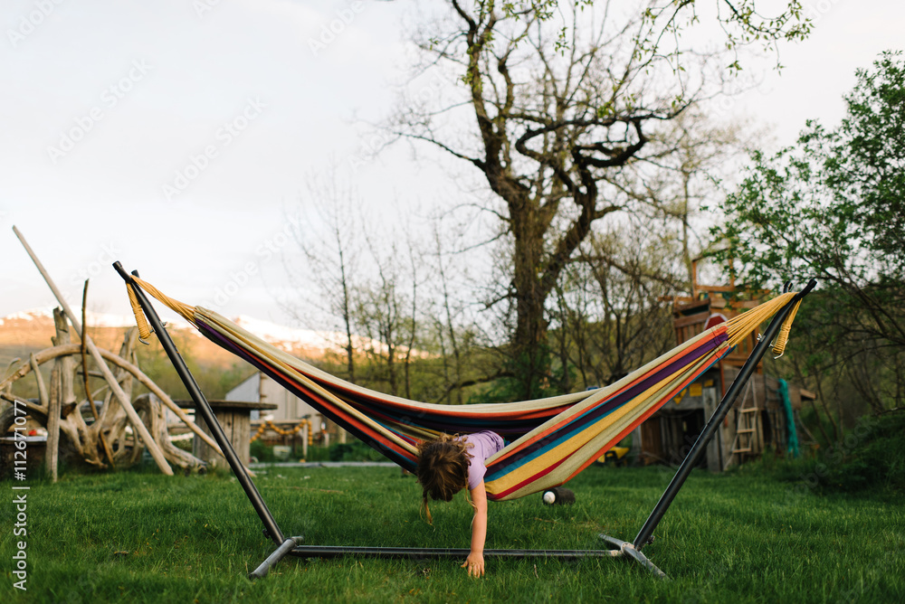 Young girl in hammock, leaning out to touch ground Young girl in hammock, leaning out to touch ground