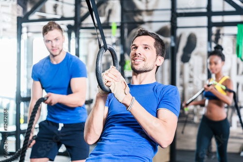 Man at rings doing fitness exercise in gym
