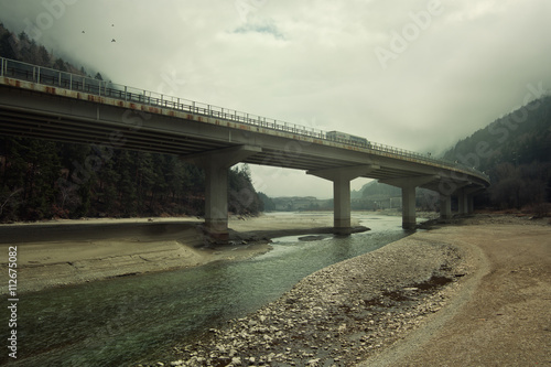 Truck crossing bridge over shallow river photo