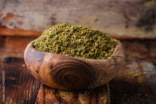 Mixed east spice - zaatar or zatar in vintage bowl on wooden background. Selective focus