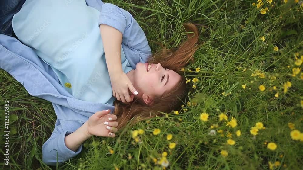 Cute girl lying in the meadow among the wildflowers. Female face close up.