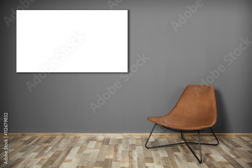 Fototapeta Naklejka Na Ścianę i Meble -  Wicker chair and picture frame on dark grey wall background