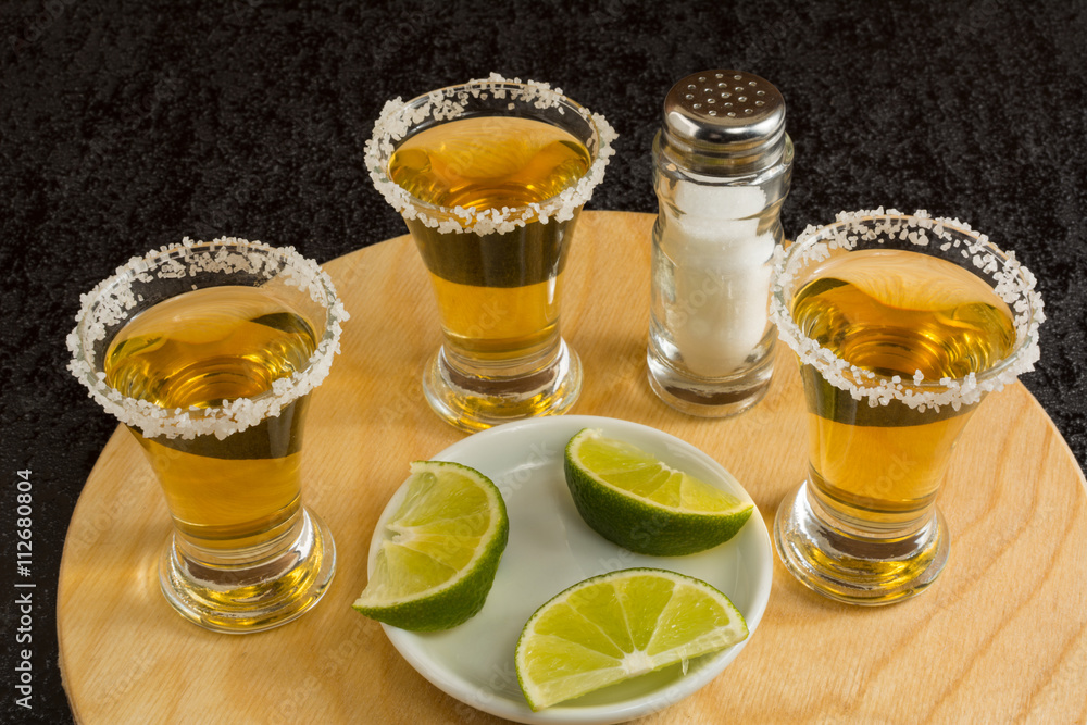 Gold tequila shots on the round wood board Gold tequila shots on the round wood board
