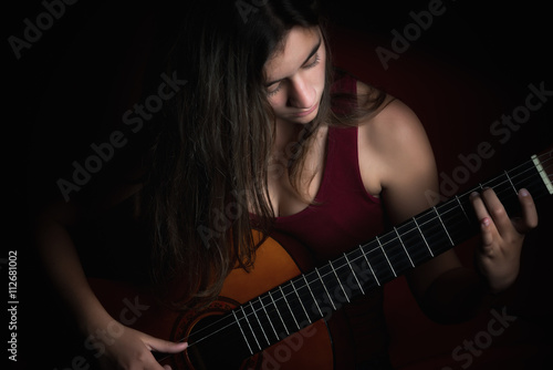 Beautiful teenage girl playing a guitar