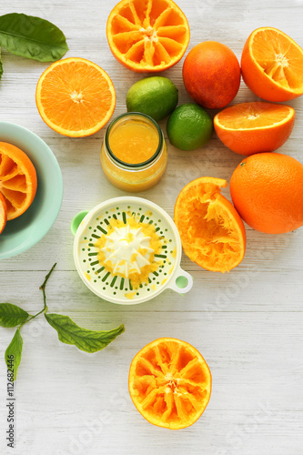 Juicy slices of oranges and juicer on white wooden table