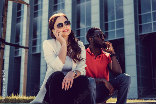 Female with smartphone in a company with afro american guy.