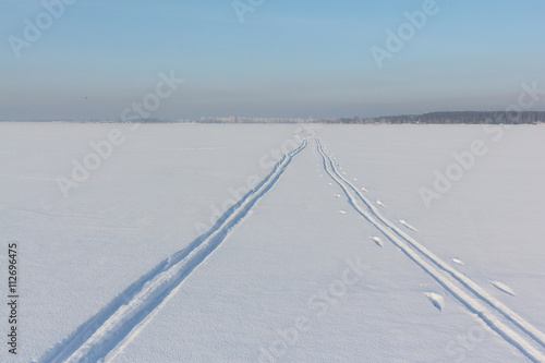 Two ski tracks leaving afar on a snow field in winter day
