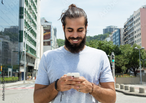 Mann mit Vollbart im grauen Shirt schreibt Nachricht photo