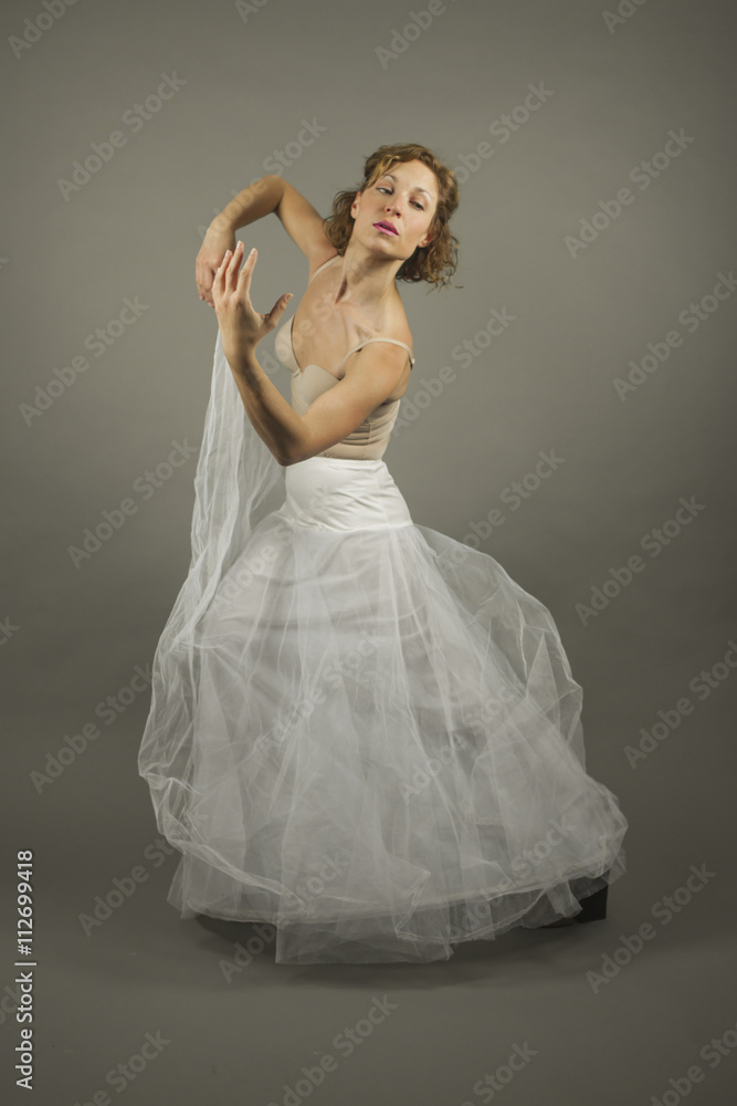 Young expressive ballerina with a white long tutu practicing bal