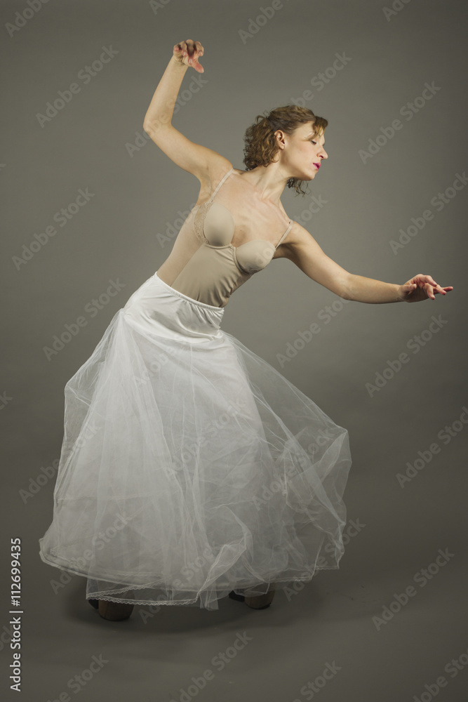 Fototapeta premium Young expressive ballerina with a white long tutu practicing bal