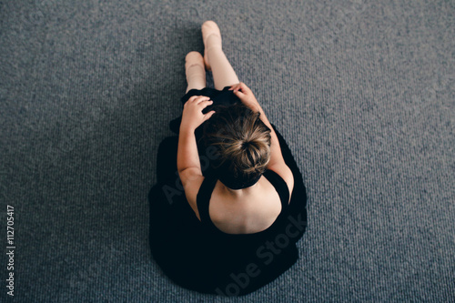 Obraz na plátně Girl in ballet leotard  and tutu doing stretches