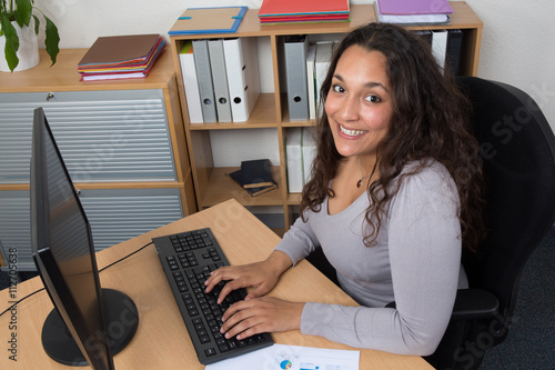 Portrait of smiling business woman at her desk with laptop