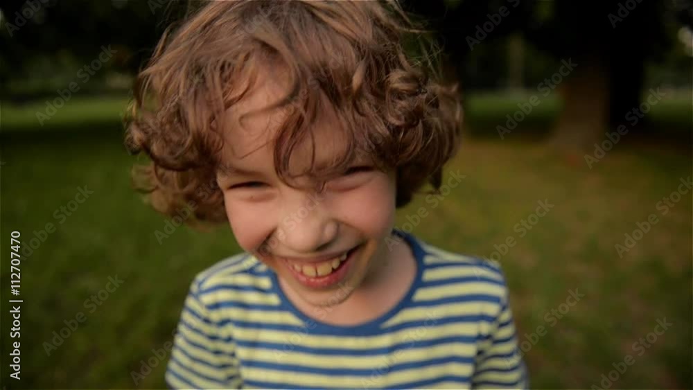 Cute boy laughing in the park, close-up, slow motion Cute boy laughing in the park, close-up, slow motion