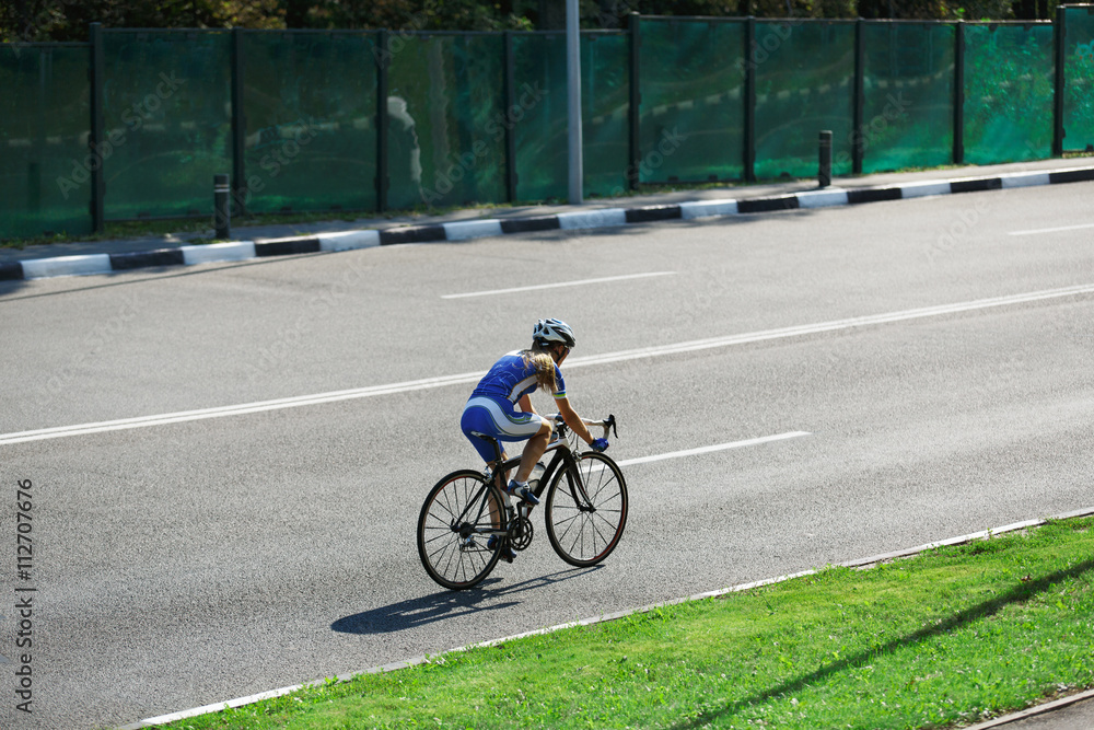 Fototapeta premium Female cyclist rides a racing bike on road